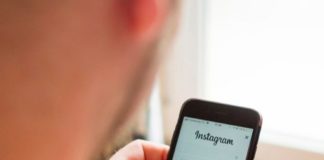 Un jeune homme manipulant son téléphone avec une page Instagram sur l'écran.